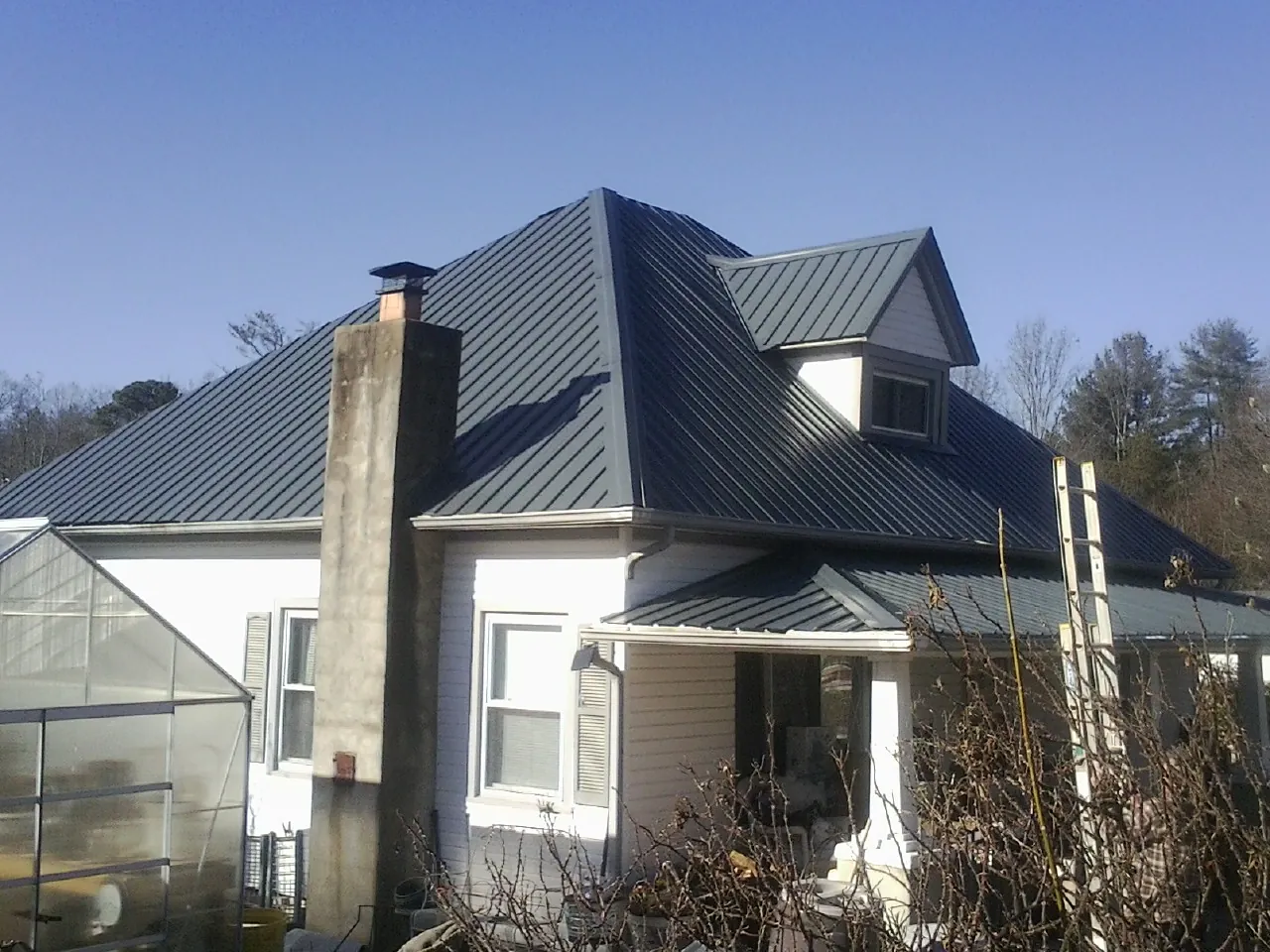 Dark blue standing seam metal roof on a white farmhouse with dormer — Slate & Tile Roof Repair by Roofing Brothers in Salt Point