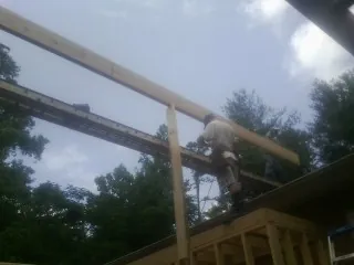 Carpenter setting a ridge beam over a new addition frame — Ice Dam Removal by Roofing Brothers in Salt Point