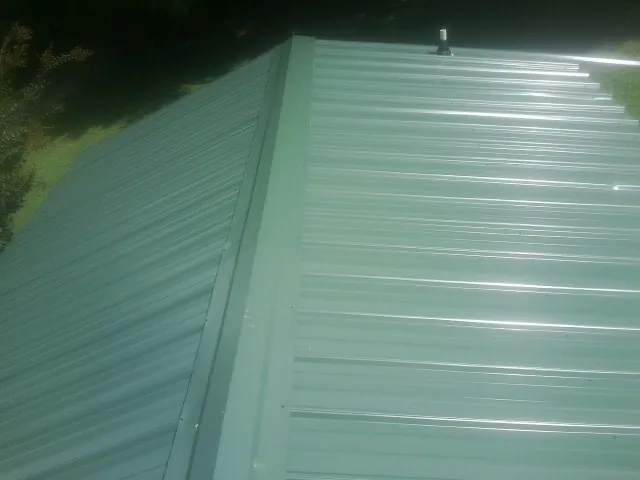 New green metal panels meeting at the ridge of a roof — Flat Roof Repair work by our crew in Salt Point