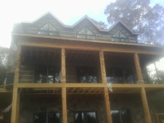 Dormers and porch framing on a large log home under construction — Roof Coating work by our crew in Salt Point
