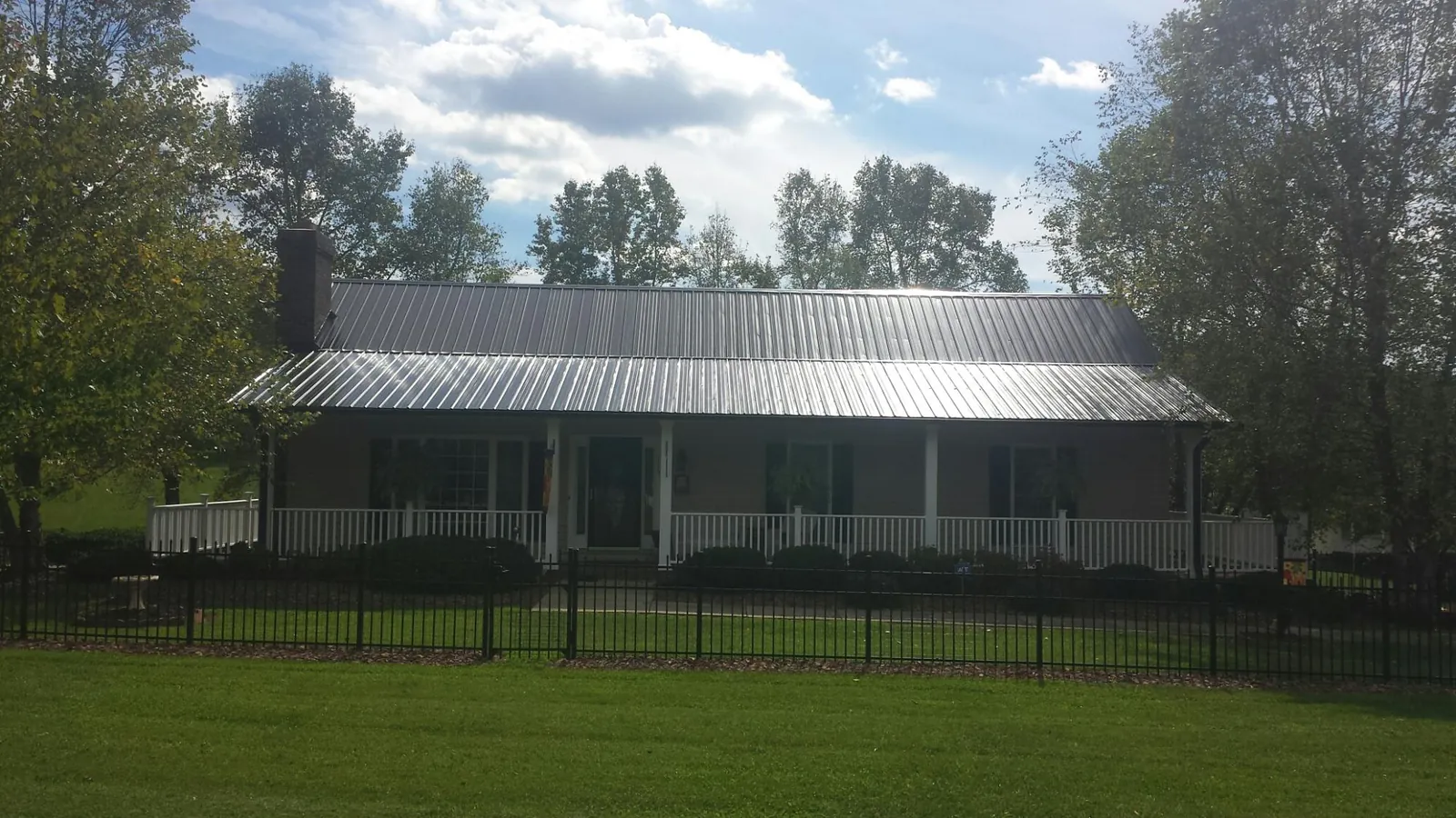 Gray metal roof on a brick ranch with a full width front porch — Gutter Guard Installation work by our crew in Salt Point