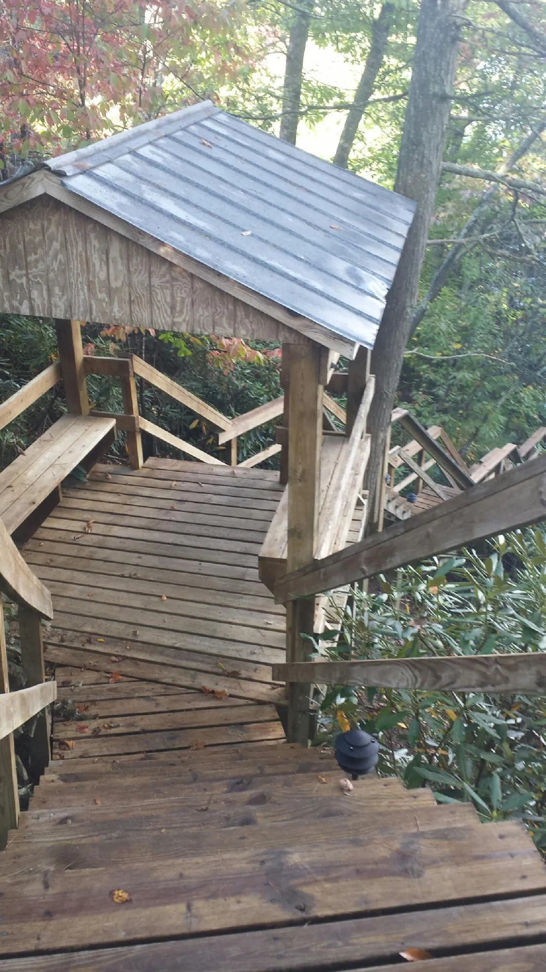 Metal roofed shelter over wooden steps on a wooded walkway — Skylight Repair & Installation work by our crew in Salt Point