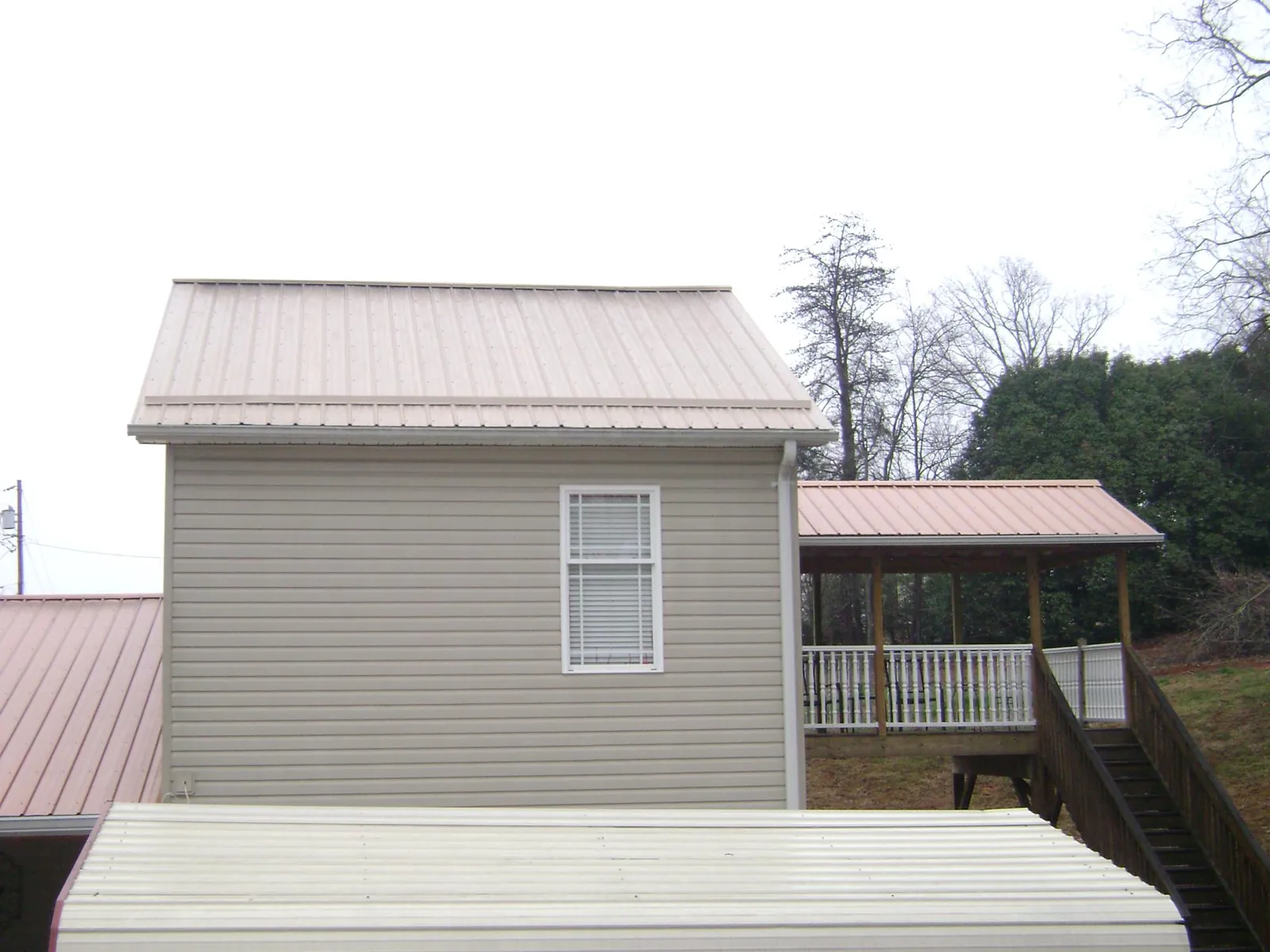 Tan metal roofs on a two story addition and attached porch, from a Roof Replacement job in Salt Point