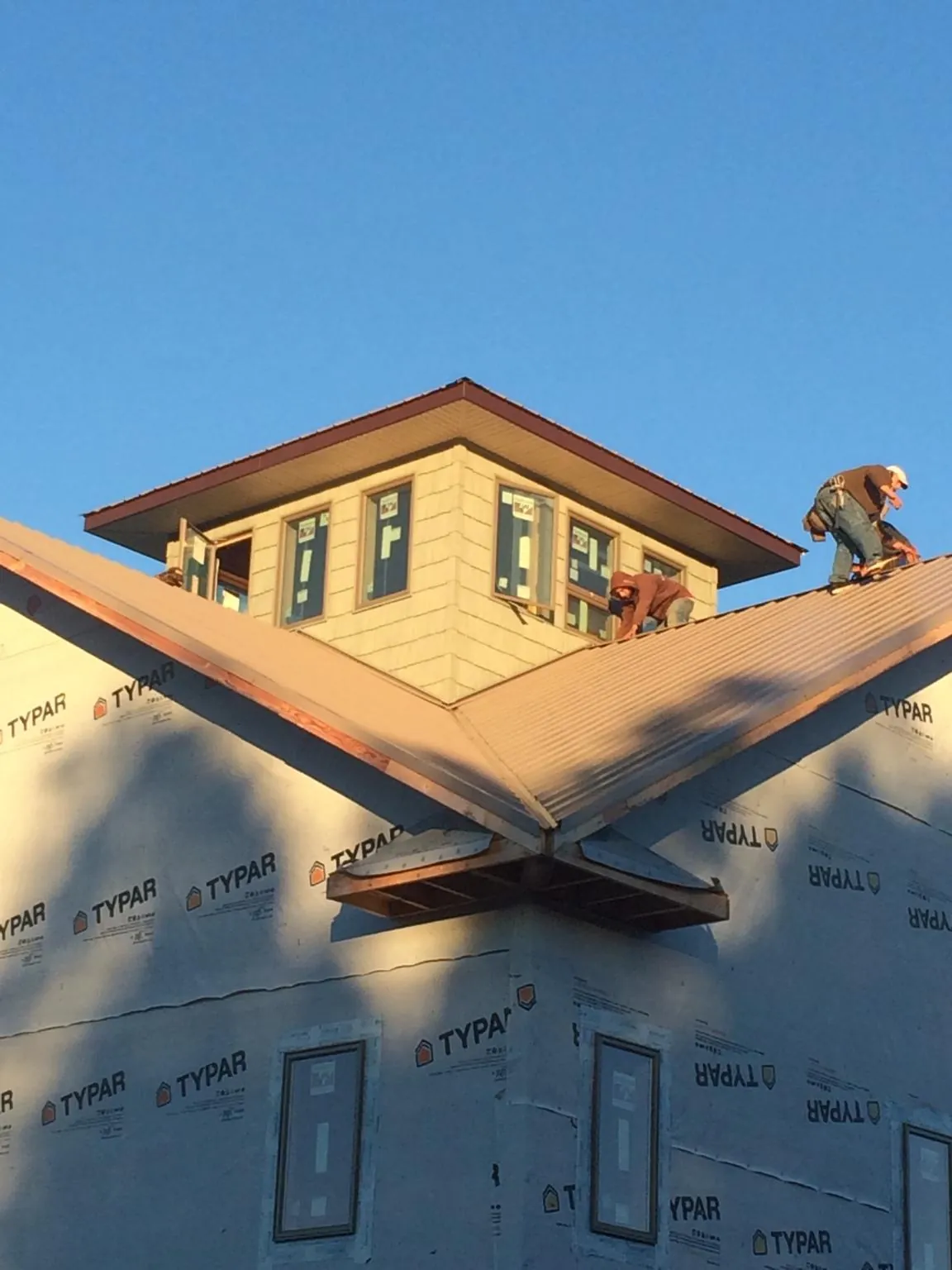 Roofers working around a rooftop cupola on a new metal roof at sunset — Roof Waterproofing in Salt Point by Roofing Brothers